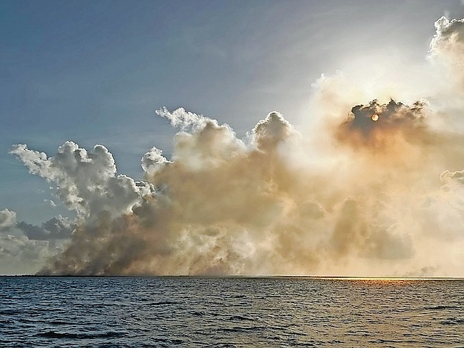 Clouds of smoke block the sun coming from the debris site outside of Treasure Cay, as seen from a distance.