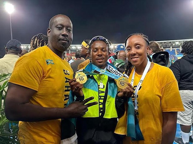 Cayden Smith flashes a smile holding his two gold CARIFTA medals with his mother, Terrell Reid, and stepfather, Enock Bonheur.