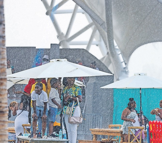 Residents find shelter under umbrellas during a rainstorm yesterday in Nassau.
Photo: Austin Fernander