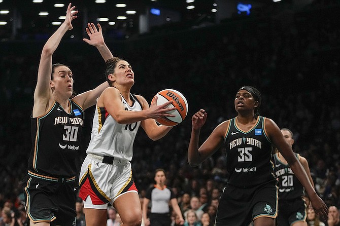 Las Vegas Aces' Kelsey Plum (10) drives past New York Liberty's Breanna Stewart (30) and Jonquel Jones (35) during the first half in Game 4 of a WNBA basketball final playoff series Wednesday, Oct. 18, 2023, in New York. (AP Photo/Frank Franklin II)