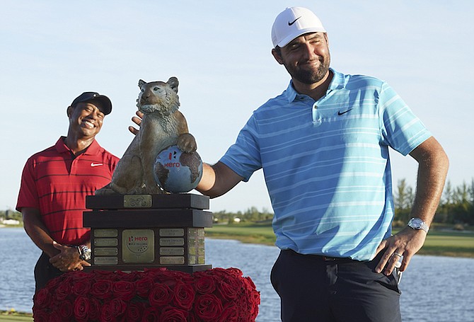 Scottie Scheffler, of the United States, right, poses with the trophy next to Tiger Woods, of United States, after winning the Hero World Challenge PGA Tour at the Albany Golf Club, in New Providence, Bahamas, Sunday, Dec. 3, 2023. (AP Photo/Fernando Llano)