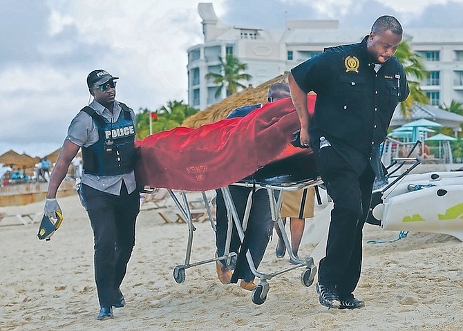 Mortuary services personnel transport the body of a female tourist after what police described as a fatal shark attack in waters near Sandals Royal Bahamian resort yesterday.  Photo: Dante Carrer