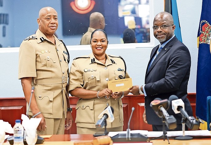 NEW ACP Janet McKenzie receives her promotion from National Security Minister Wayne Munroe yesterday; Police Chief Clayton Fernander stands at her left. She will oversee the Human Resource and Domestic Violence Unit.
Photos: Moise Amisial
