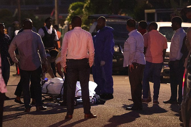 MORTUARY services personnel remove the body of a male from the scene on Nicoll's Street where three men were shot resulting in two deaths yesterday.
Photo: Dante Carrer