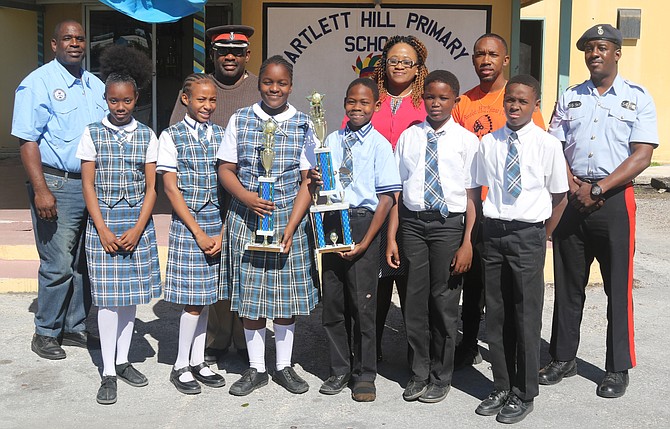 BARTLETT Hill Primary boys and girls teams celebrate their basketball chmpionships. Along with the students, shown from left to right are Sergeant 269 Reserve William, ASP Lee Capron, and Denika Martin, principal of Bartlett Hill Primary School.