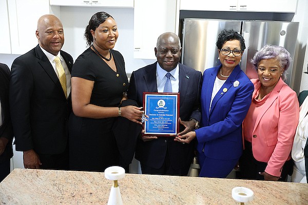 Minister of Housing and Urban Renewal Keith Bell, Prime Minister Philip “Brave” Davis, Ann Marie Davis and Bahamas Mortgage Corporation Chairman Barbara Cartwright present a plaque to new homeowner Barcia McIntosh during an event where new homeowners are presented with keys at Renaissance at Carmichael yesterday. Photo: Dante Carrer
