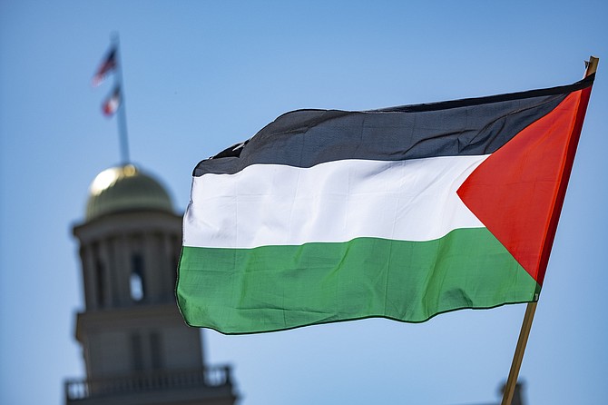 A protester waves a Palestinian flag Friday, May 3, 2024, at the Pentacrest in Iowa City, Iowa. (Geoff Stellfox/The Gazette via AP)