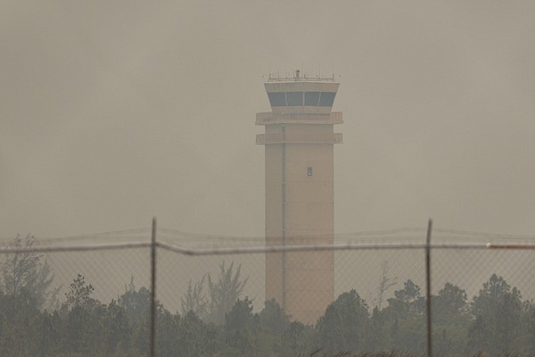 The Lynden Pindling International Airport control tower is obscured by smoke from a bush fire along Coral Harbour Rd on May 14, 2024. Photo: Dante Carrer/Tribune Staff