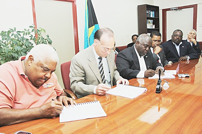 Stanley Bethell, left, proprietor of Bethell’s Trucking and Heavy Equipment is pictured signing a contract to reconstruct roads in Andros. Also shown beginning is Colin Higgs, from second left, permanent secretary in the Ministry of Works and Urban Development; Deputy Prime Minister Philip Davis; Perry Gomez, Minister of Health; Arnold Forbes, Minister of State in the Ministry of Works and Urban Development; and George Hutcheson, Deputy Director. Photo: Raymond A Bethel, Sr/BIS