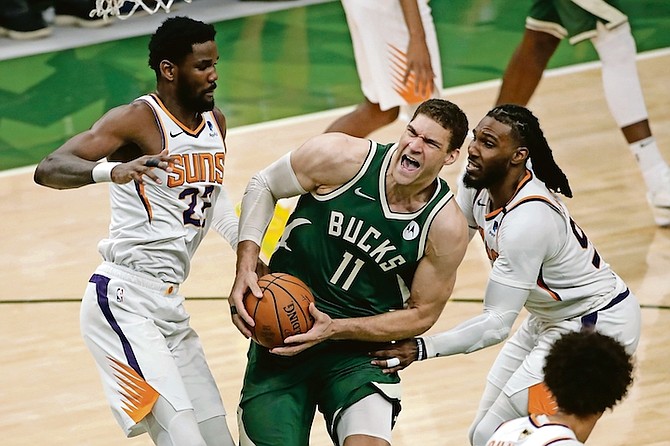 Milwaukee Bucks' Brook Lopez (11) is fouled as he drives between Phoenix Suns' Jae Crowder (99) and Deandre Ayton (22) during the second half of Game 3 of basketball's NBA Finals, Sunday, July 11, 2021, in Milwaukee. (AP Photo/Aaron Gash)