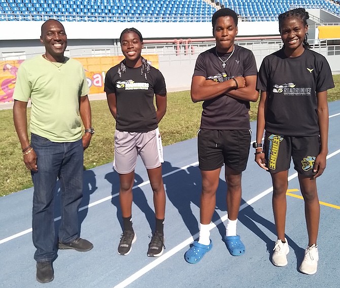 Roadrunners coach Dexter Bodie poses with CARIFTA  track team members Tamia Taylor, Trent Ford and Akaree Roberts.