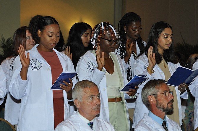 Standing far left is Bahamian Percell Collie, of Abaco, seen taking the Hippocratic Oath with other students of the Class of 2023 during the WAUSM White Coat ceremony on Saturday in GB. Bahamian Rodney Rolle (not seen) also received his white coat. 										 Photos: Vandyke Hepburn