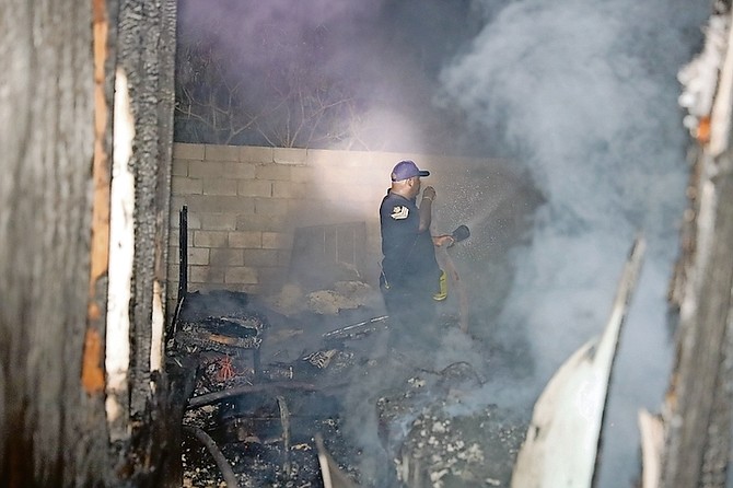 Fire personnel extinguish the flames at a shanty town in the Joe Farrington Road area, containing the spread.