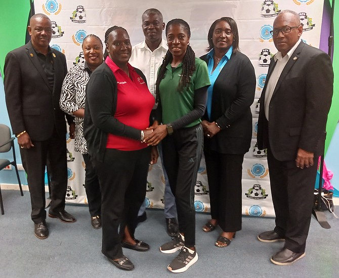 GSSSA president Varel Davis and BAISS soccer convenyer Sandre Hobbs shake hands as Floyd Armbrister, Crystal AStrachan, Bruce Swan, Oria Knowles and Carl Lynch look on.