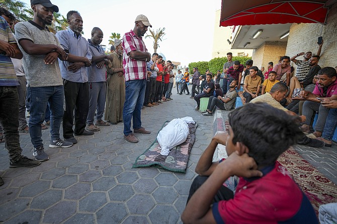 Palestinians pray next to the bodies of their relatives who were killed in an Israeli airstrike in Gaza Stirp, at the Al Aqsa hospital in Deir al Balah, Gaza Strip, Sunday, June 2, 2024. (AP Photo/Abdel Kareem Hana)