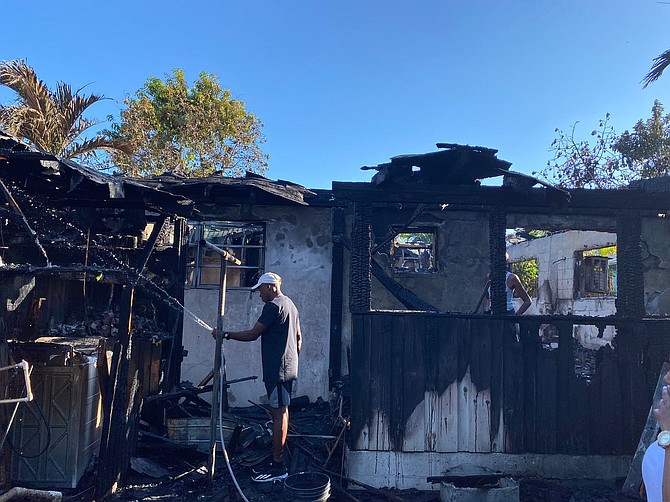 CAPTAIN Whitfield Neely spraying water on the remains of his home. Photo: Osano Neely