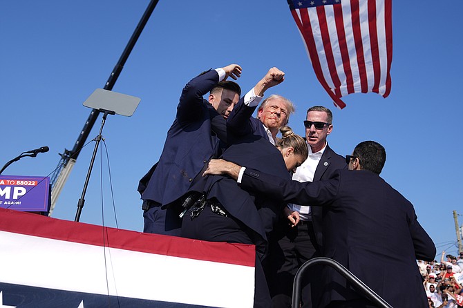 Republican presidential candidate former President Donald Trump gestures as he is surrounded by U.S. Secret Service agents as he leaves the stage at a campaign rally, Saturday, July 13, 2024, in Butler, Pa. (AP Photo/Evan Vucci)