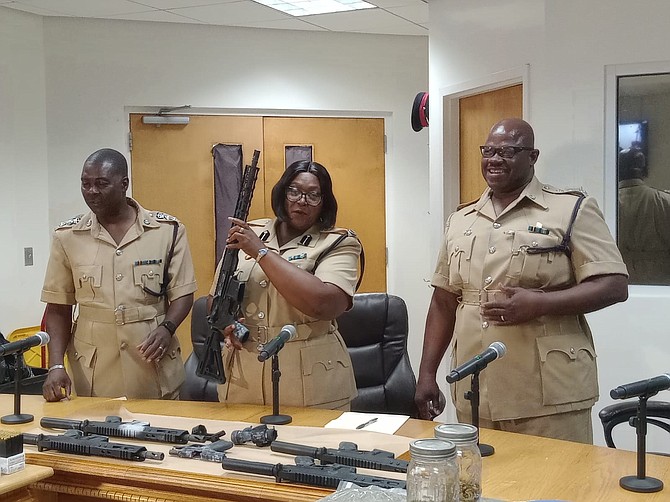 Assistant Commissioner of Police Shanta Knowles (centre) holds a high-powered rifle during a press conference revealing a stockpile of guns, ammunition and drugs seized by police from the residence of a 45-year-old man in Grand Bahama on July 29, 2024.