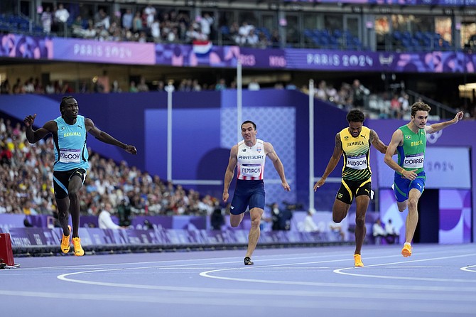 Wanya McCoy, left, of the Bahamas, crosses the finish line in a men's 200-meters' heat at the 2024 Summer Olympics, Monday, Aug. 5, 2024, in Saint-Denis, France. (AP Photo/Petr David Josek)