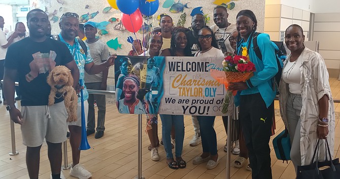 Olympian Charisma Taylor is flanked by her family members on her arrival home.