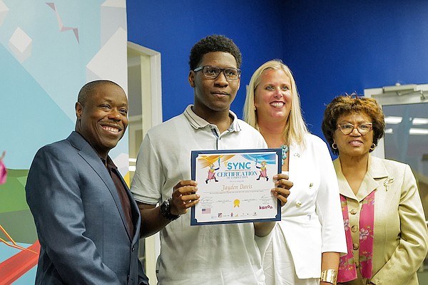 Kanoo CEO Keith Davies, US Chargé d’Affaires Kimberly Furnish and Permanent Secretary Lorraine Symonette-Armbrister present Jayden Davis with a certificate of completion for the SYNC (Science, Youth, Nation building, and Culture) Junkanoo Entrepreneurship Program at the University of The Bahamas on August 27, 2024. Photo: Dante Carrer/Tribune Staff