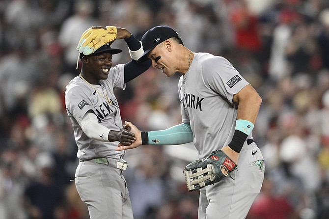 New York Yankees center fielder Aaron Judge, right, celebrates the catch he made on a fly ball by Washington Nationals' Andres Chaparro for an out with New York Yankees third baseman Jazz Chisholm Jr., left, during the fourth inning of a baseball game, Monday, Aug. 26, 2024, in Washington. (AP Photo/Nick Wass)