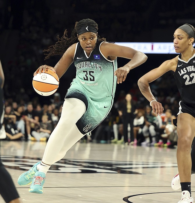 New York Liberty forward Jonquel Jones (35) commands the ball near Las Vegas Aces center A'ja Wilson (22) during a WNBA basketball semifinal game Friday, Oct. 4, 2024, in Las Vegas. (AP Photo/Ronda Churchill)