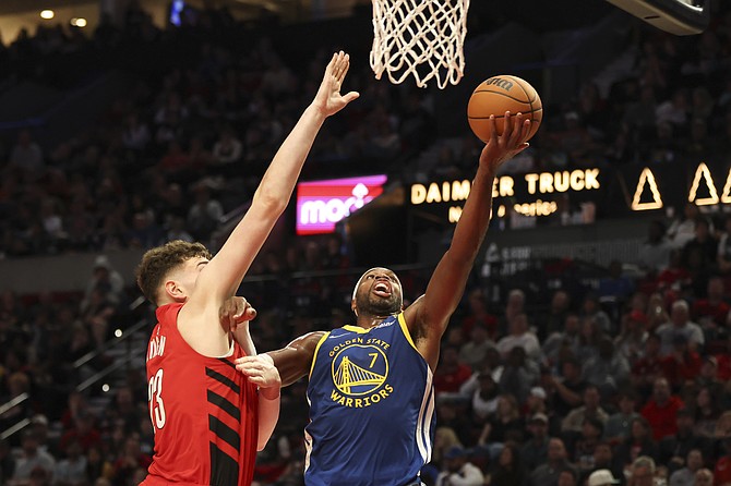 Golden State Warriors guard Buddy Hield (7) drives to the basket as Portland Trail Blazers center Donovan Clingan (23) defends during the second half of an NBA basketball game Wednesday, Oct. 23, 2024, in Portland, Ore. (AP Photo/Amanda Loman)