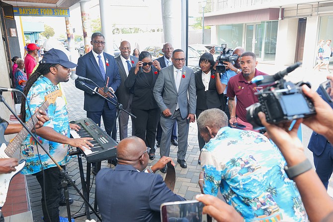 Tourism Minister Chester Cooper plays the saw with a sidewalk band near the new Incubator Centre for Artisans on Shirley Street during the official opening yesterday. Photos: Nikia Charlton