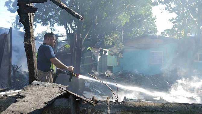 Firemen at the scene where fire left four families without a home on Dunmore Street yesterday. Photos: Nikia Charlton