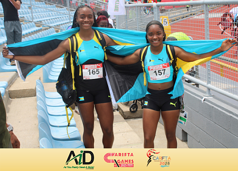 Taysha Stubbs (left) and Dior-Rae Scott pose with the Bahamian flag at the 2025 CARIFTA Games on April 19, 2025. Photo Brent Stubbs