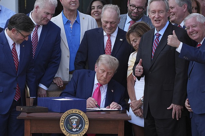 President Donald Trump signs his signature bill of tax breaks and spending cuts at the White House, Friday, July 4, 2025, in Washington, surrounded by members of Congress. (AP Photo/Evan Vucci)