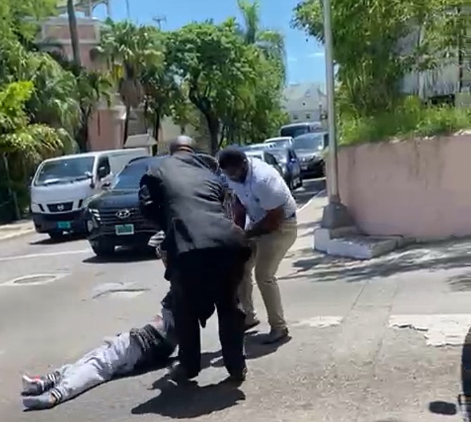 Screen capture from video showing man being dragged across Shirley Street by plain clothes officers.