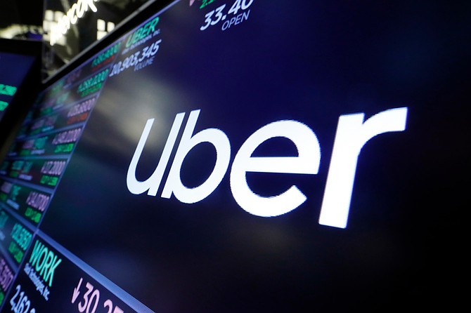 The Uber logo appears above a trading post on the floor of the New York Stock Exchange, Aug. 16, 2019. (AP Photo/Richard Drew, File)
