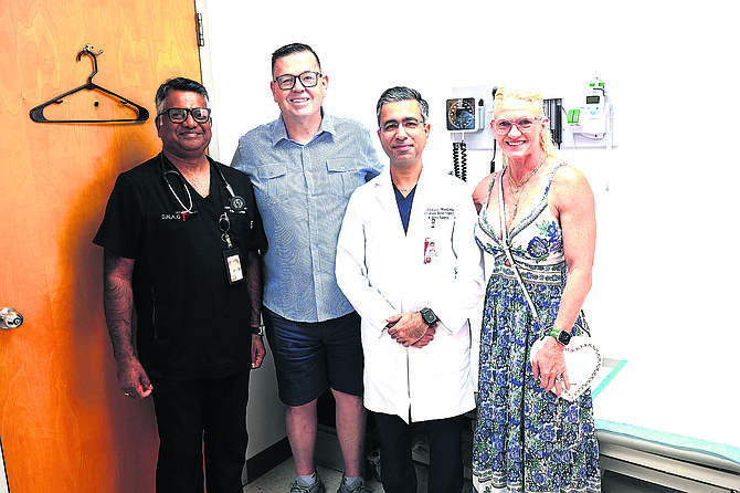 DR SUSHEEL WADHWA (white coat) points to a brain scan on a computer screen as he meets with former patient Ray Wood and his wife Raemie. Photo: Nikia Charlton