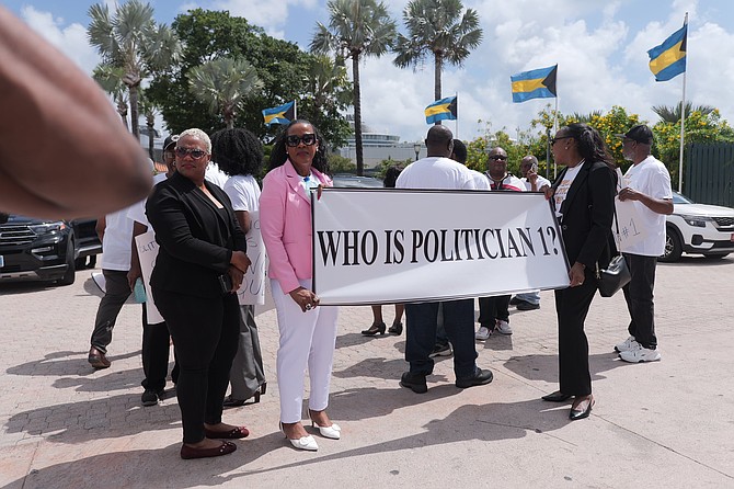 A dozen protesters carrying signs questioning the identity of “Politician-1” outside Parliament on May 27, 2026. Photo Chappell Whyms Jr