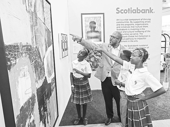 A MOMENT of inspiration: Scotiabank Bahamas Managing Director Roger Archer shares a work by Bahamian artist Jason Bennett with students from St. Francis & Joseph Catholic Primary School, encouraging them to see the possibilities for their own creativity. The piece was featured in Sco- tiabank’s art exhibition at FUZE.